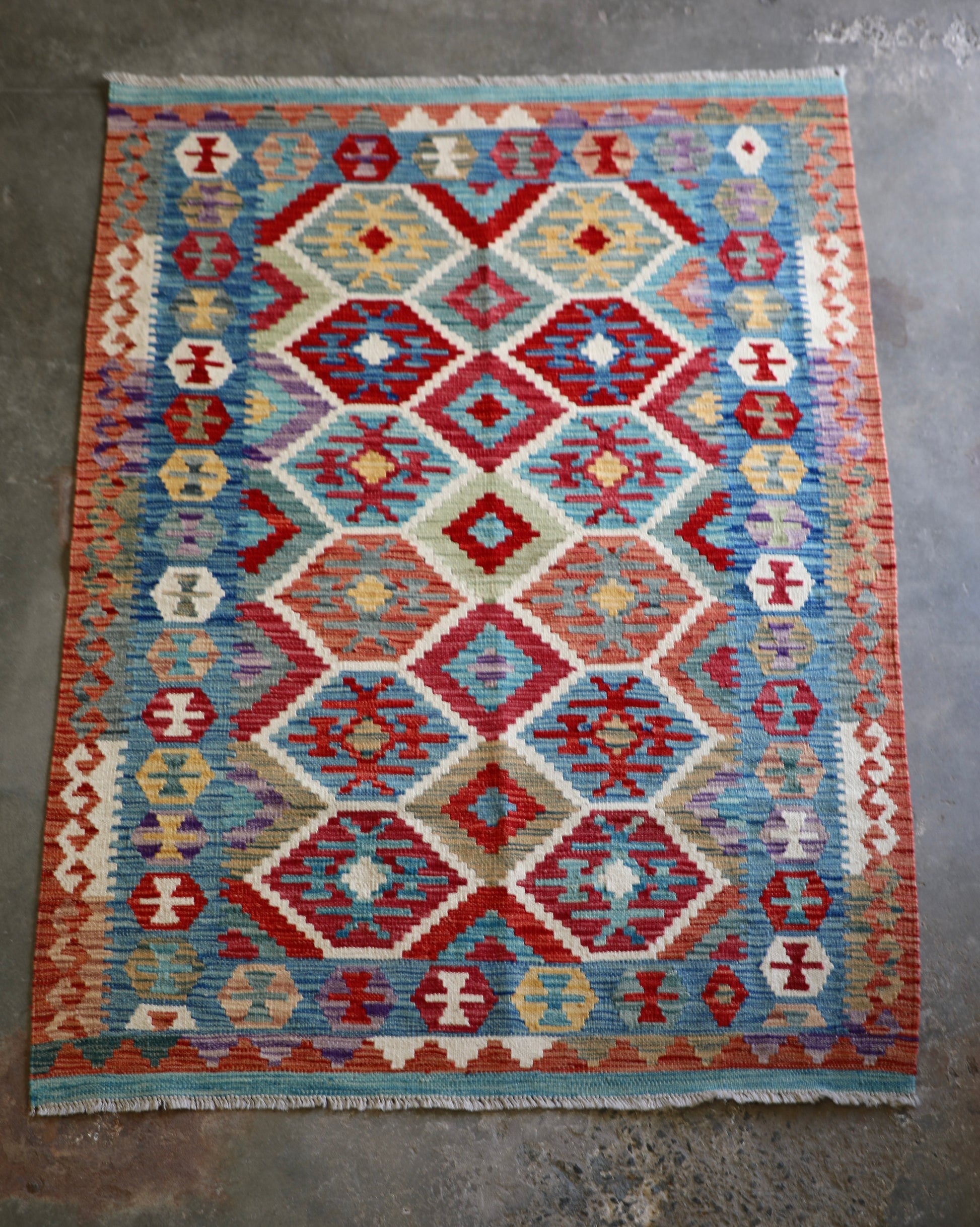 The Afghan Hand Woven Khyber Kilim - 129 X 178.  Crafted using traditional vegetable dyed wool, and featuring traditional geometric designs. Colours, brown, red, blue, cream, teal. Size 129 X 178. Front.