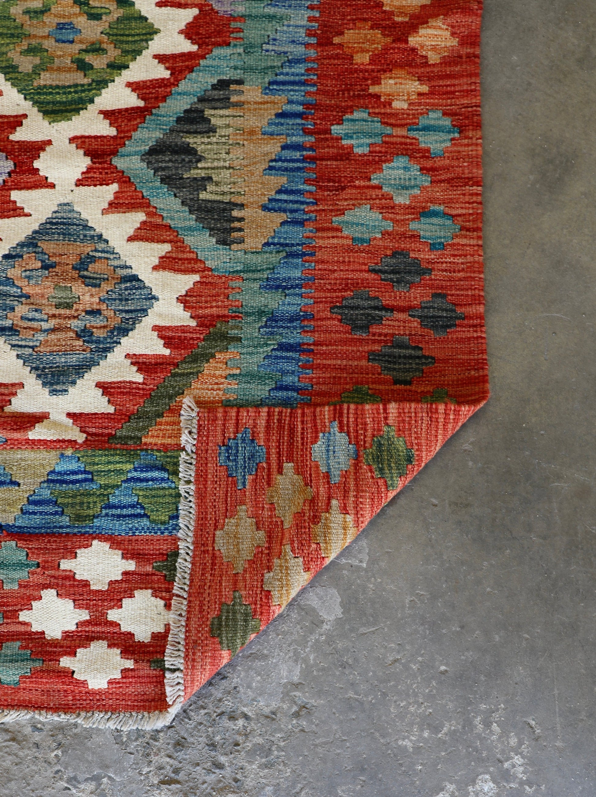 The Afghan Hand Woven Khyber Kilim - 172 X 250. Crafted using traditional vegetable dyed wool, and featuring traditional geometric designs. Colours, cream, reds, greens, blues, oranges. Size 172 X 250. Fold.