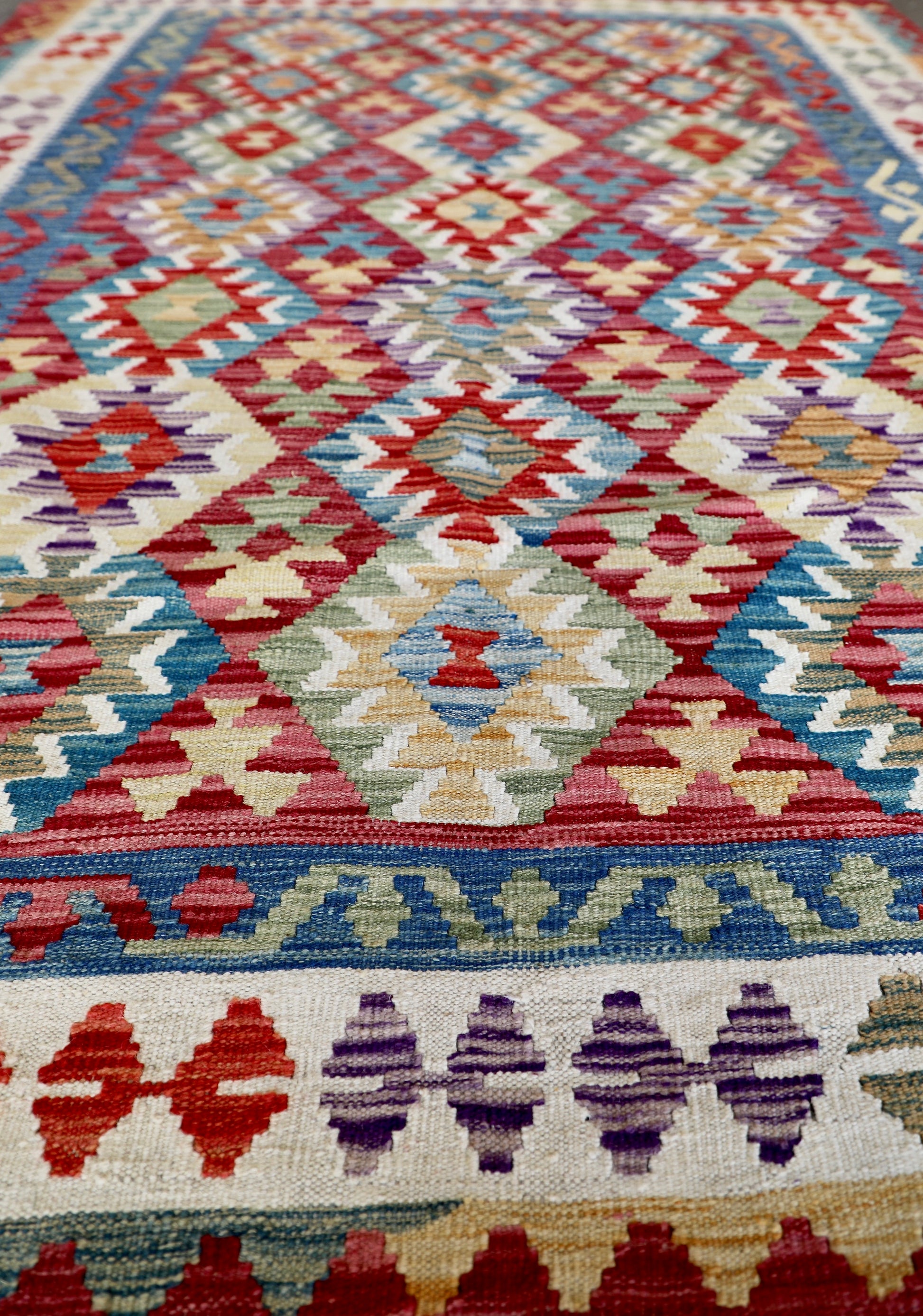 The Afghan Hand Woven Khyber Kilim - 175 X 240. Crafted using traditional vegetable dyed wool, and featuring traditional geometric designs. Colours, red, blue, yellow, teal, beige. Size 175 X 240. Angle.
