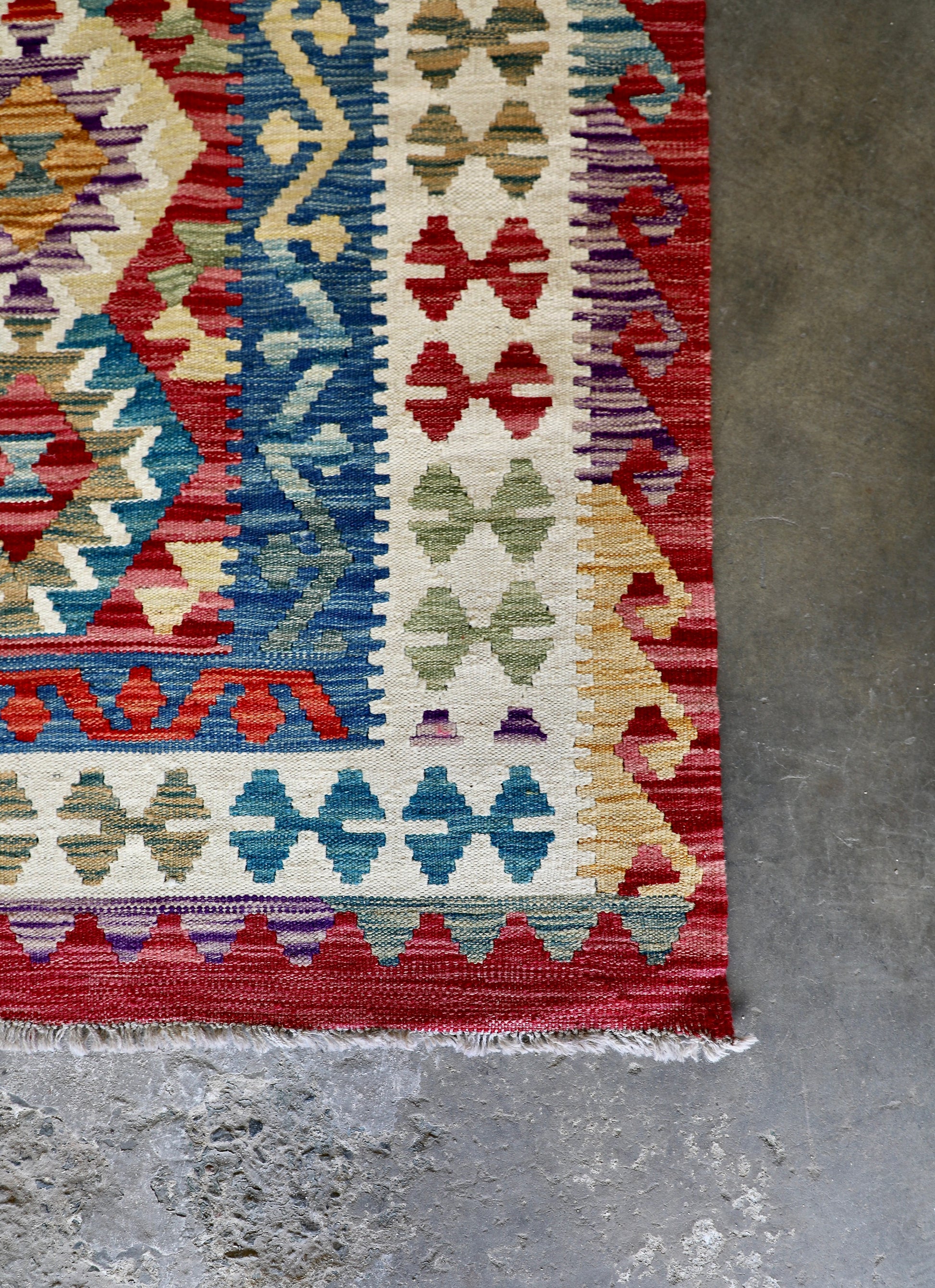 The Afghan Hand Woven Khyber Kilim - 175 X 240. Crafted using traditional vegetable dyed wool, and featuring traditional geometric designs. Colours, red, blue, yellow, teal, beige. Size 175 X 240. Corner.