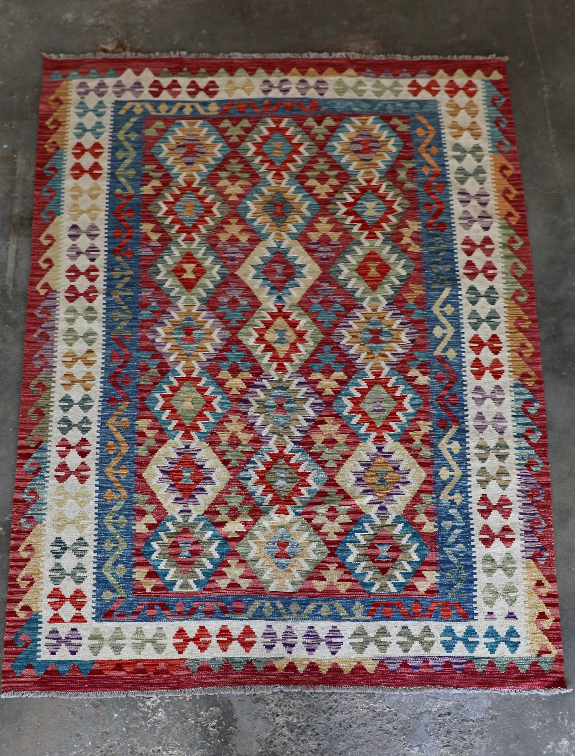 The Afghan Hand Woven Khyber Kilim - 175 X 240. Crafted using traditional vegetable dyed wool, and featuring traditional geometric designs. Colours, red, blue, yellow, teal, beige. Size 175 X 240. Front.
