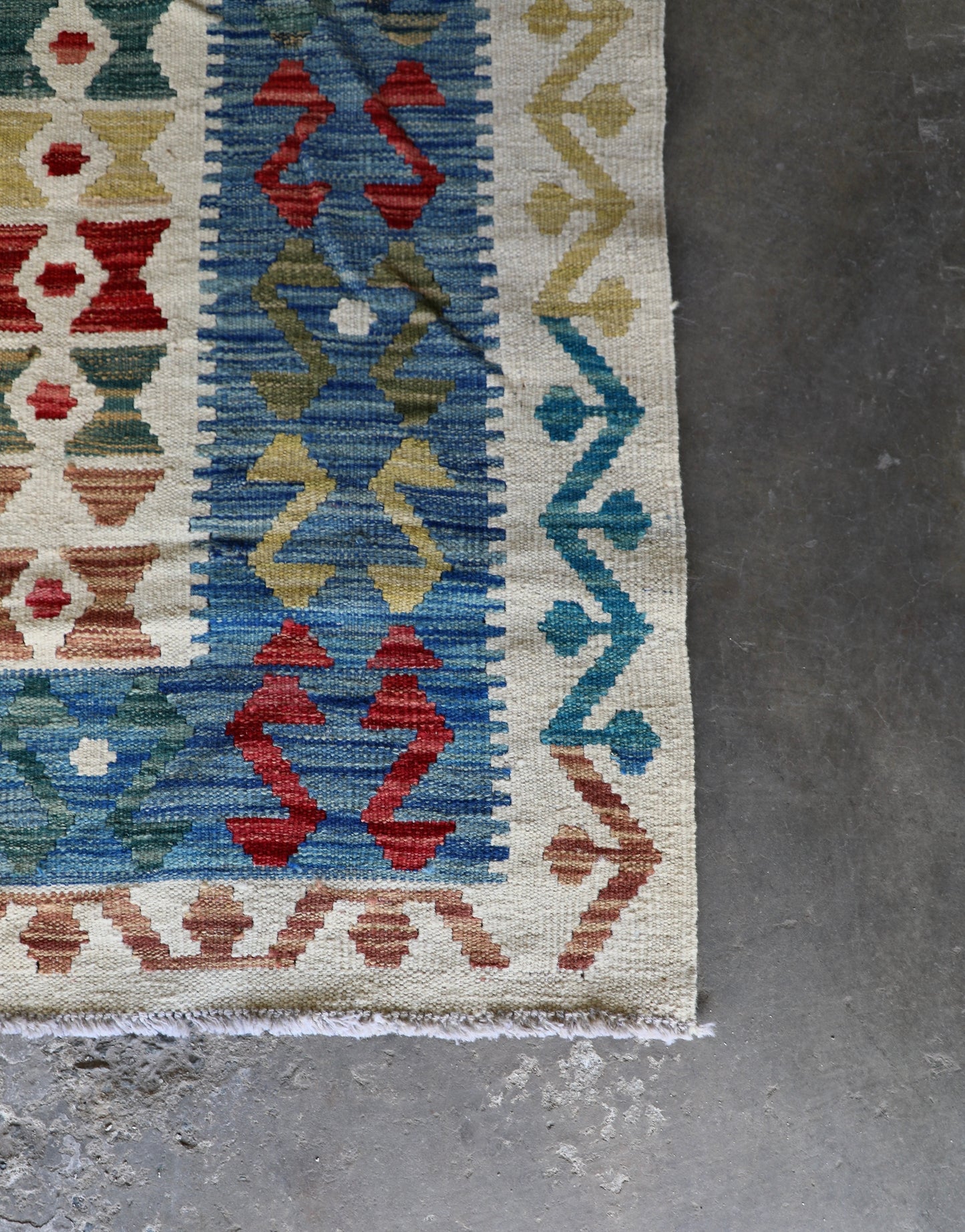 The Afghan Hand Woven Khyber Kilim - 180 X 248. Crafted using traditional vegetable dyed wool, and featuring traditional geometric designs. Colours, cream, blues, greens, reds, oranges. Size 180 X 248. Corner.
