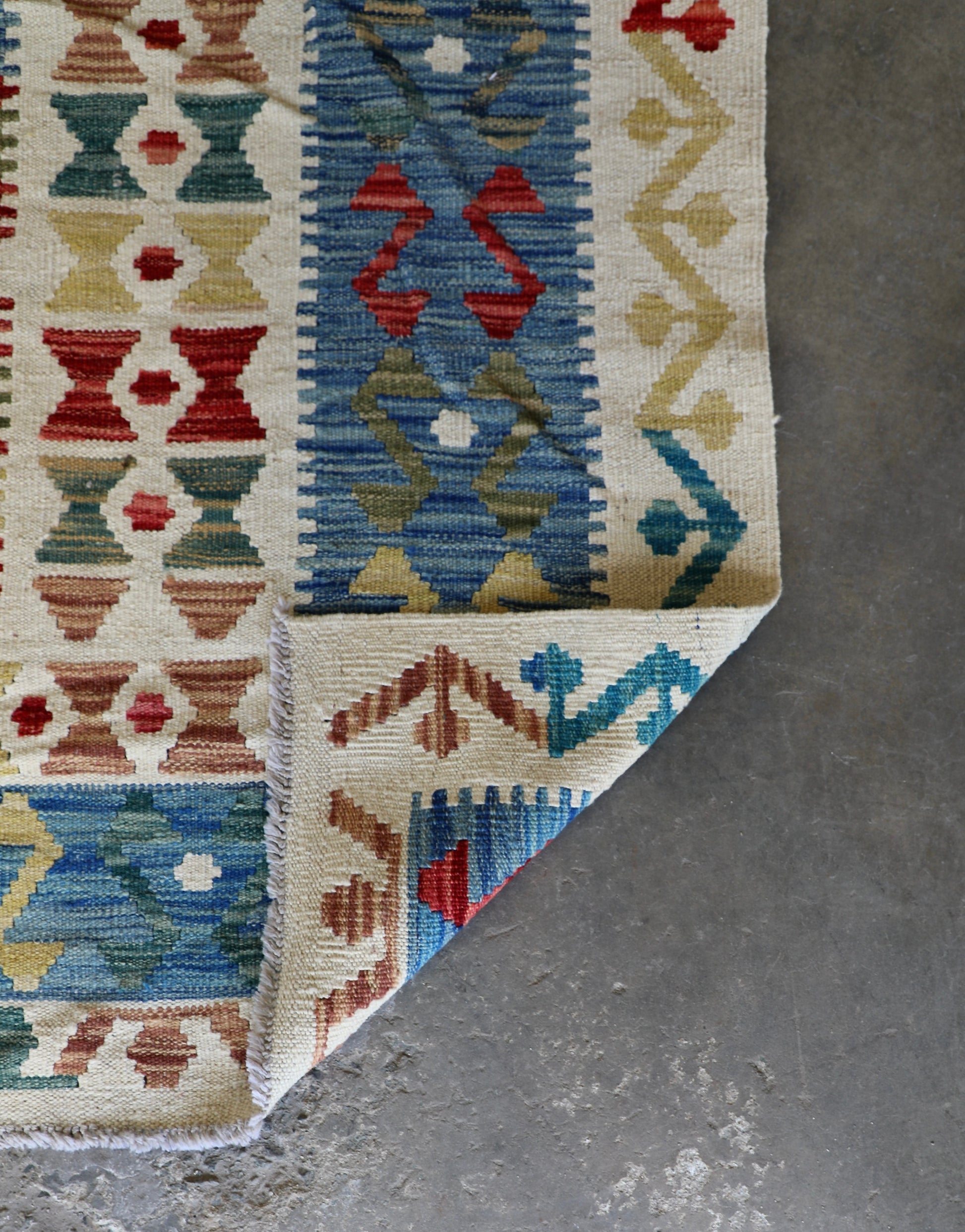 The Afghan Hand Woven khyber Kilim - 180 X 248. Crafted using traditional vegetable dyed wool, and featuring traditional geometric designs. Colours, cream, blues, greens, reds, oranges. Size 180 X 248. Fold.
