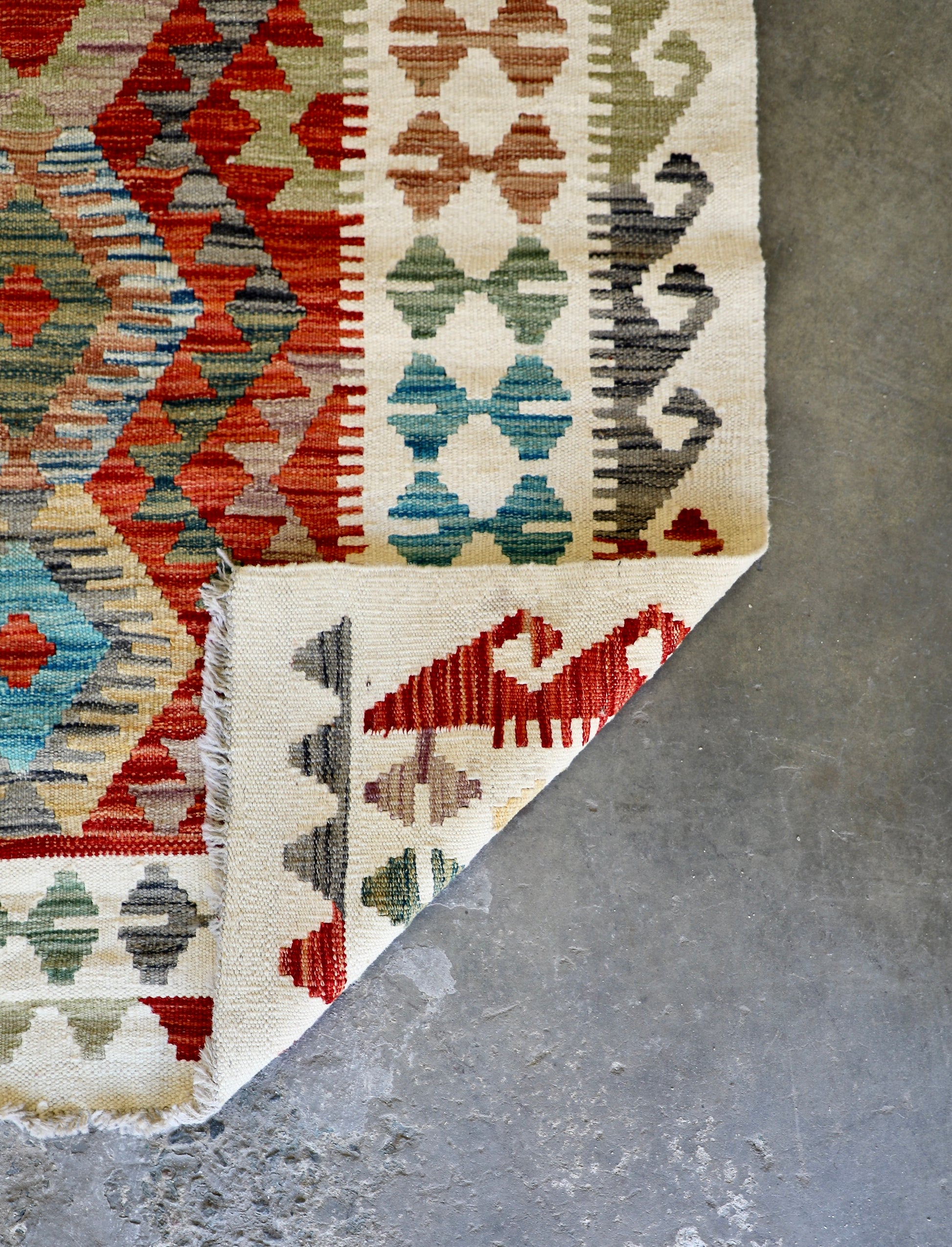 The Afghan Hand Woven Khyber Kilim - 184 X 250. Crafted using traditional vegetable dyed wool, and featuring traditional geometric designs. Colours, cream, reds, oranges, teals, yellows. Size 184 X 250. Fold.