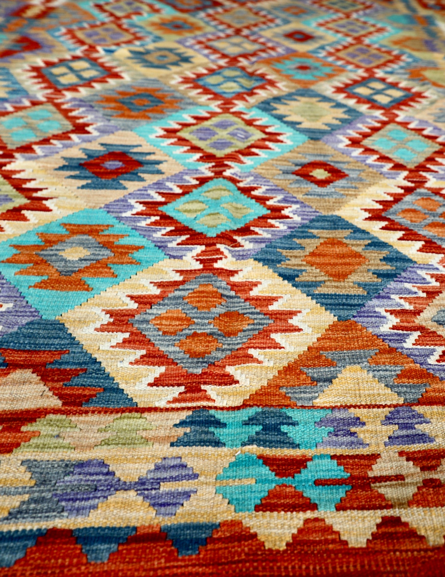 The Afghan Hand Woven Khyber Kilim - 202 X 286. Crafted using traditional vegetable dyed wool, and featuring traditional geometric designs. Colours, reds, blues, greens, yellows and oranges. Size 202 X 286. Angle.
