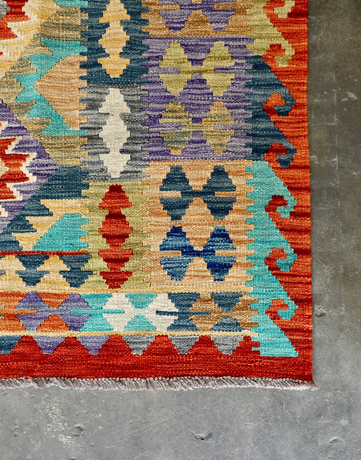 The Afghan Hand Woven Khyber Kilim - 202 X 286. Crafted using traditional vegetable dyed wool, and featuring traditional geometric designs. Colours, reds, blues, greens, yellows and oranges. Size 202 X 286. Corner.