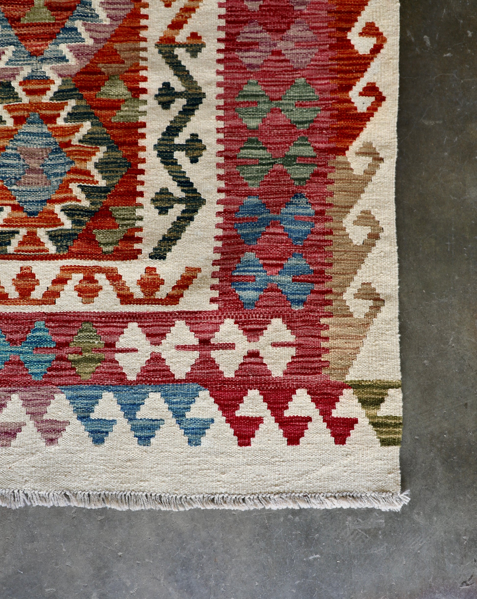 The Afghan Hand Woven Wool Khyber Kilim - 206 X 296.  Crafted using traditional vegetable dyed wool, and featuring traditional geometric designs. Colours, cream, reds, oranges, teals, blues and beiges. Size 206 X 296. Corner.
