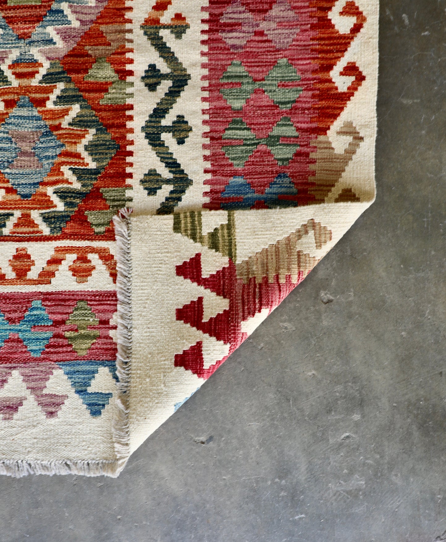 The Afghan Hand Woven Wool Khyber Kilim - 206 X 296.  Crafted using traditional vegetable dyed wool, and featuring traditional geometric designs. Colours, cream, reds, oranges, teals, blues and beiges. Size 206 X 296. Fold.