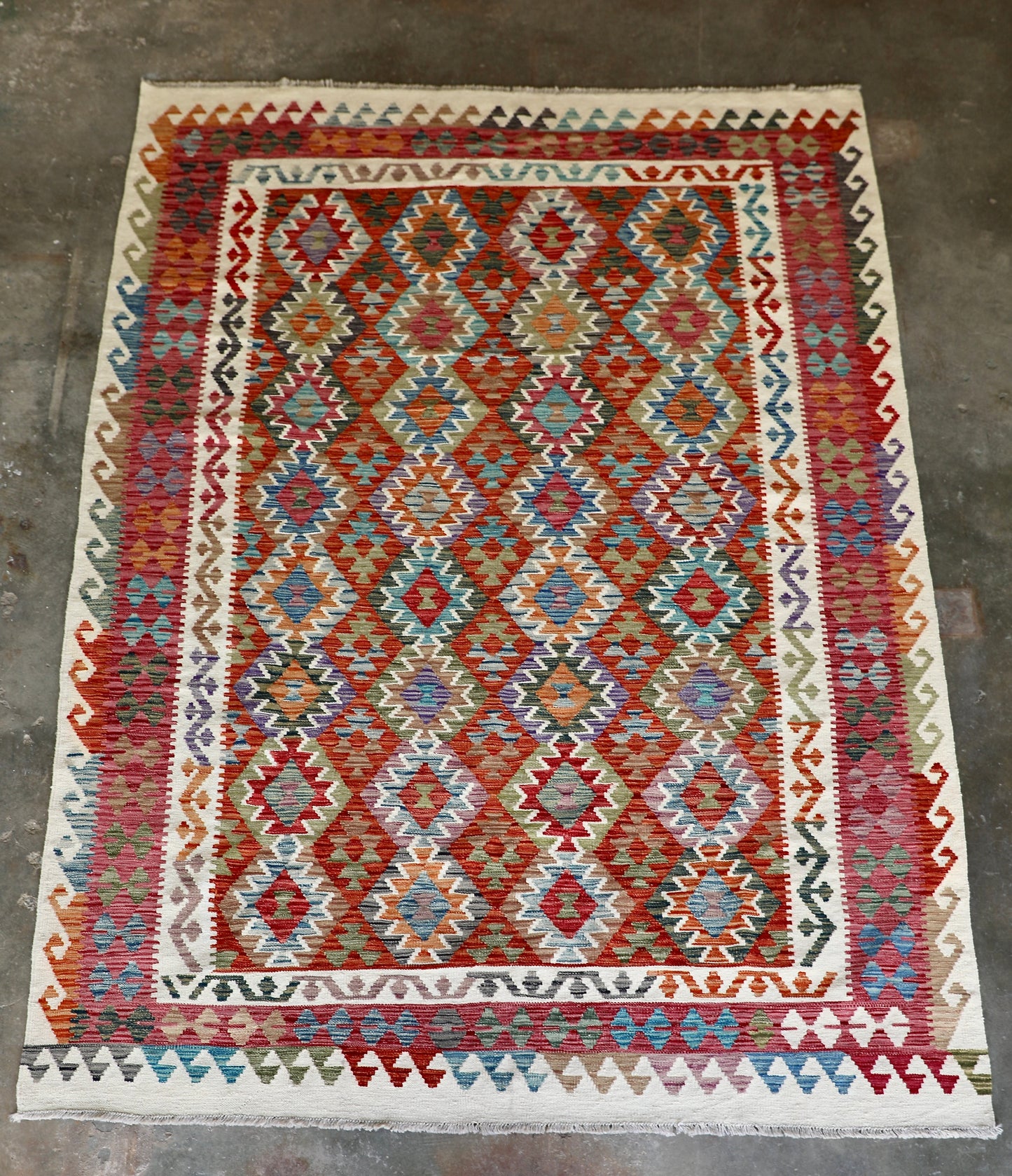 The Afghan Hand Woven Wool Khyber Kilim - 206 X 296.  Crafted using traditional vegetable dyed wool, and featuring traditional geometric designs. Colours, cream, reds, oranges, teals, blues and beiges. Size 206 X 296. Front.