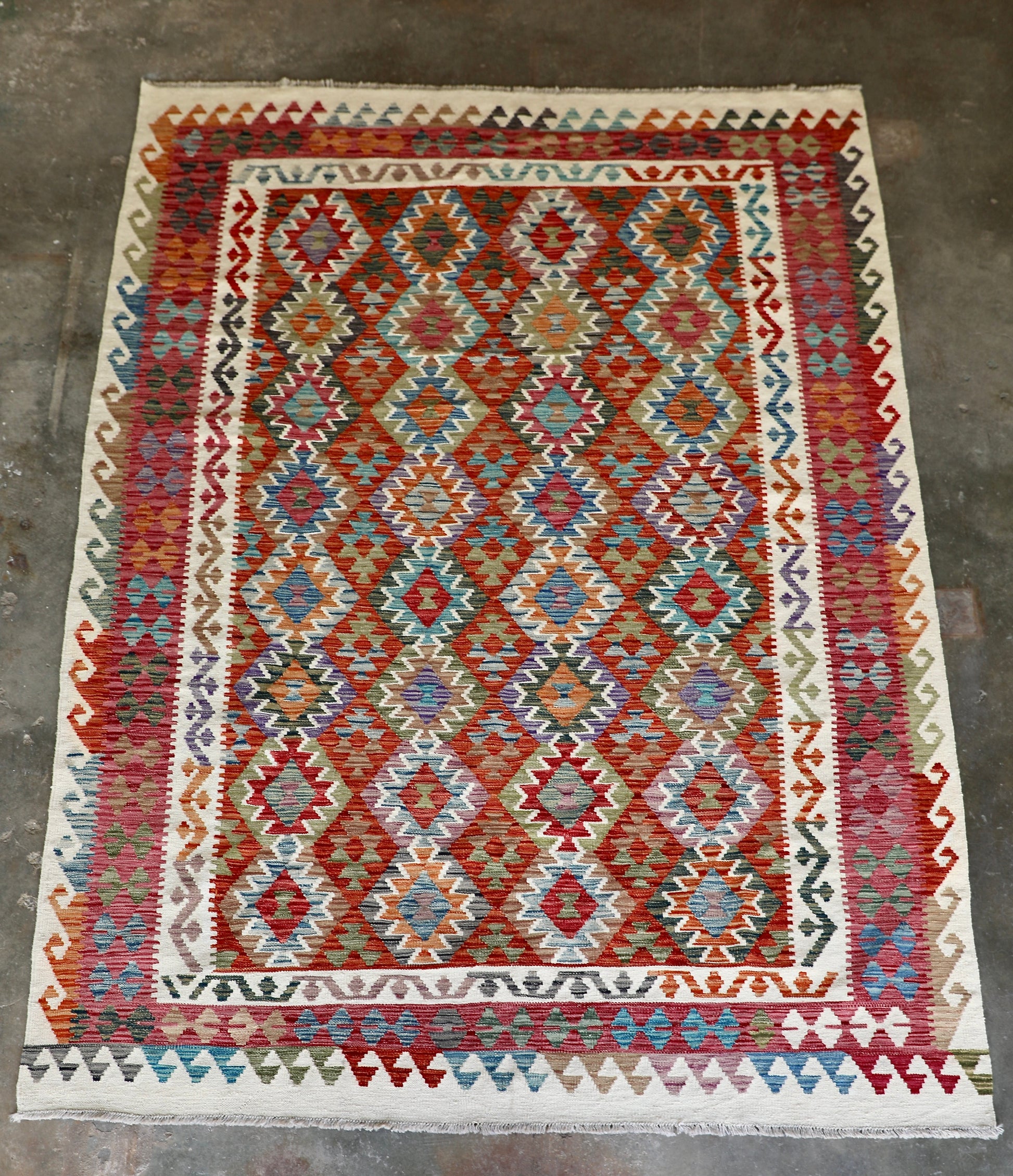 The Afghan Hand Woven Wool Khyber Kilim - 206 X 296.  Crafted using traditional vegetable dyed wool, and featuring traditional geometric designs. Colours, cream, reds, oranges, teals, blues and beiges. Size 206 X 296. Front.