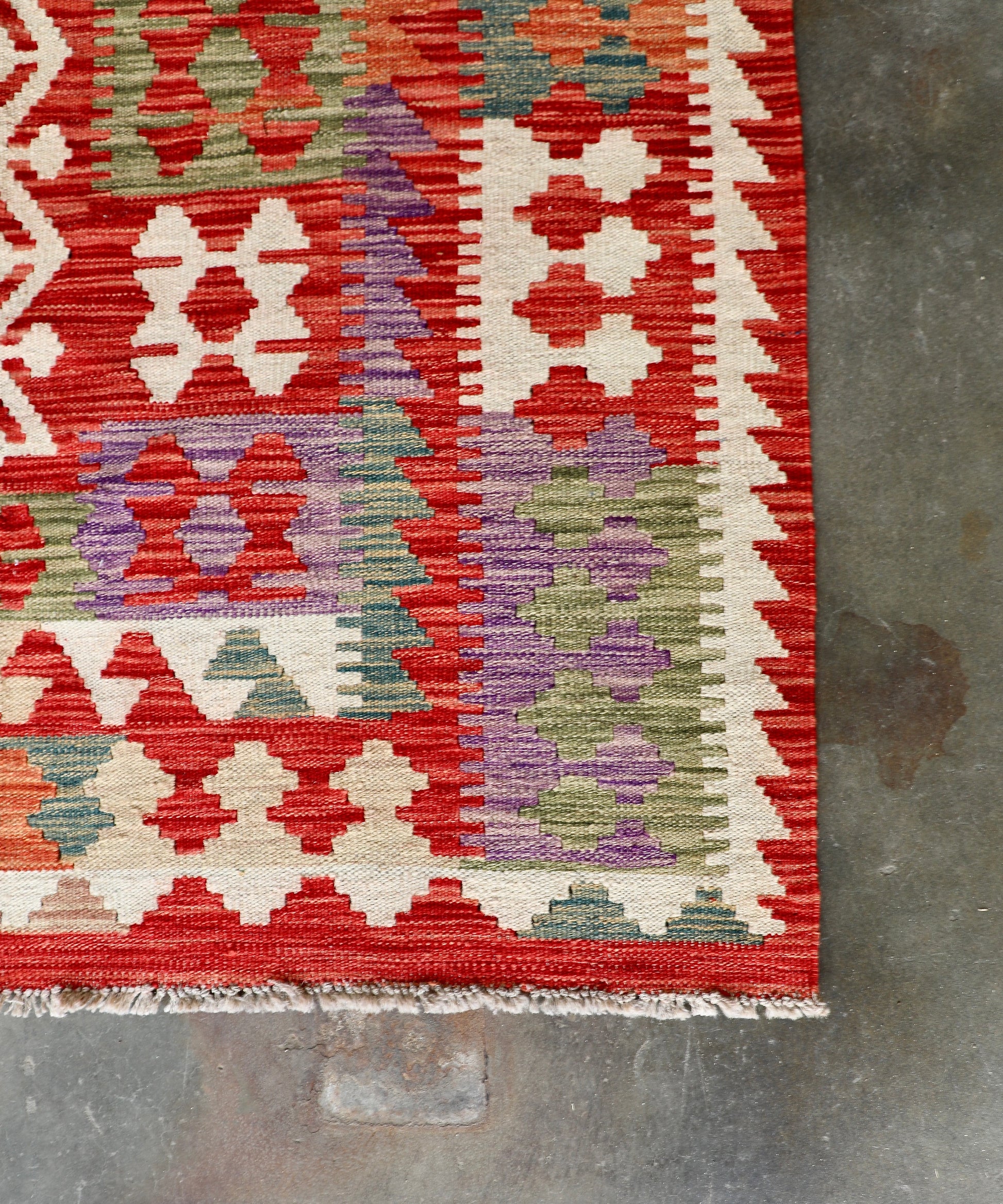 The Afghan Hand Woven Khyber Kilim - 252 X 345. Crafted using traditional vegetable dyed wool, and featuring traditional geometric designs. Colours, Oranges, reds, creams, teals. Size 252 X 345. Corner.