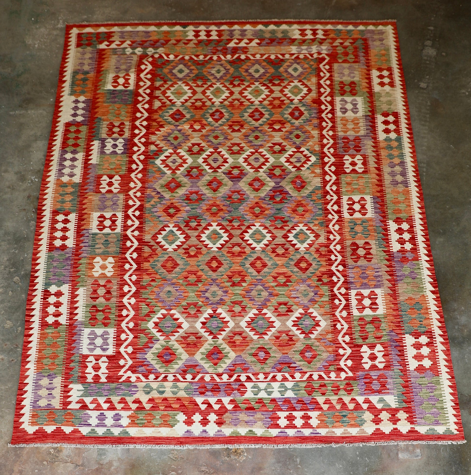 The Afghan Hand Woven Khyber Kilim - 252 X 345. Crafted using traditional vegetable dyed wool, and featuring traditional geometric designs. Colours, Oranges, reds, creams, teals. Size 252 X 345. Front.