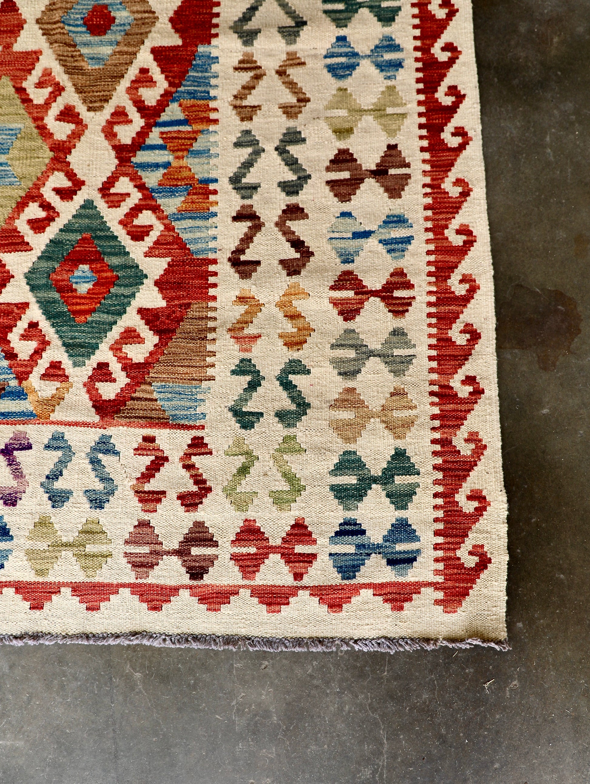The Afghan Hand Woven Khyber Kilim - 278 X 376. Crafted using traditional vegetable dyed wool, and featuring traditional geometric designs. Colours, cream, blues, reds, oranges, yellow and teals. Size 278 X 376. Corner.