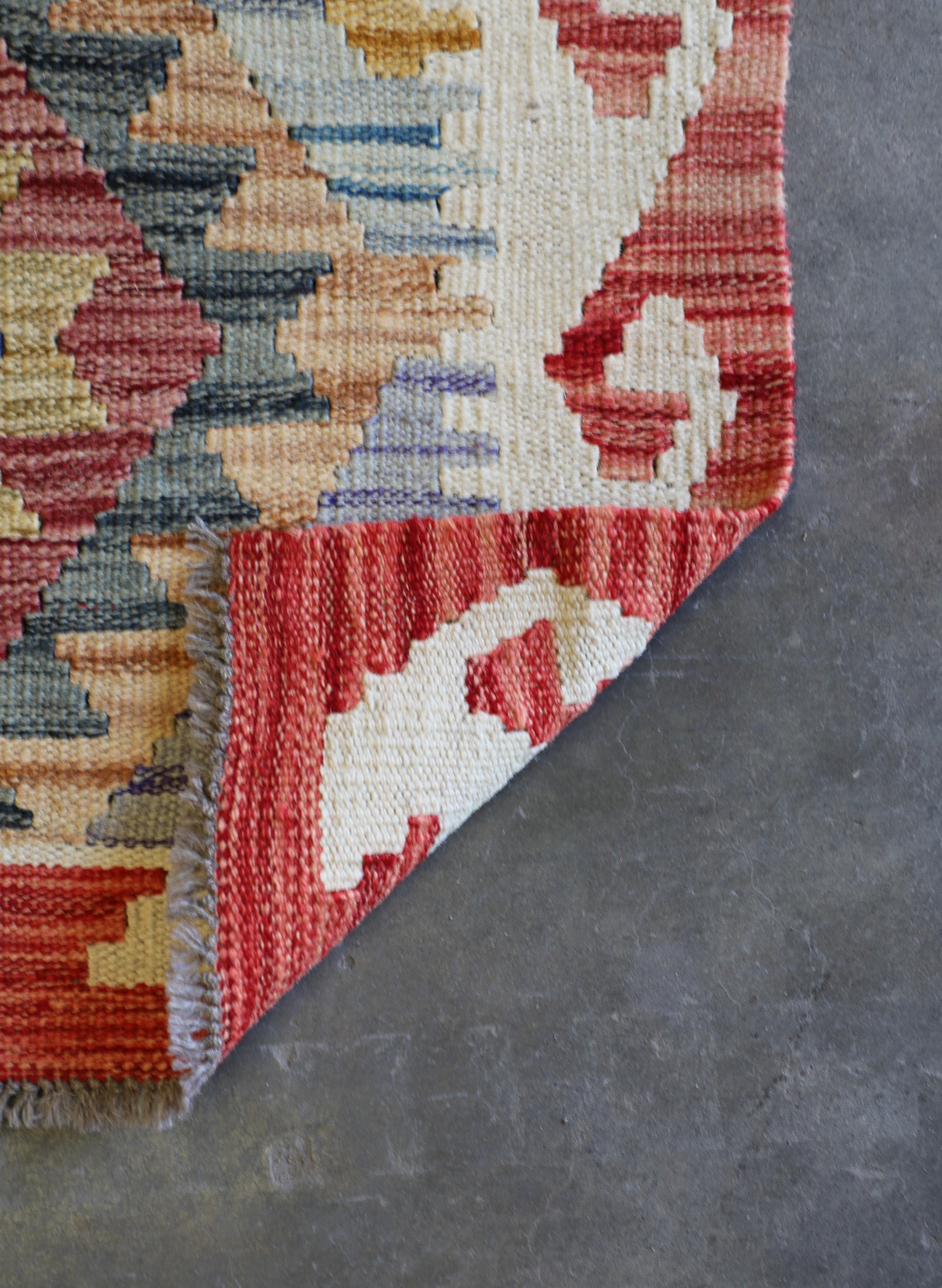 The Afghan Hand Woven Khyber Kilim - 62 X 92. Crafted using traditional vegetable dyed wool, and featuring traditional geometric designs. Colours, oranges, creams, light blues, dark greens. Size 62 X 92. Fold.
