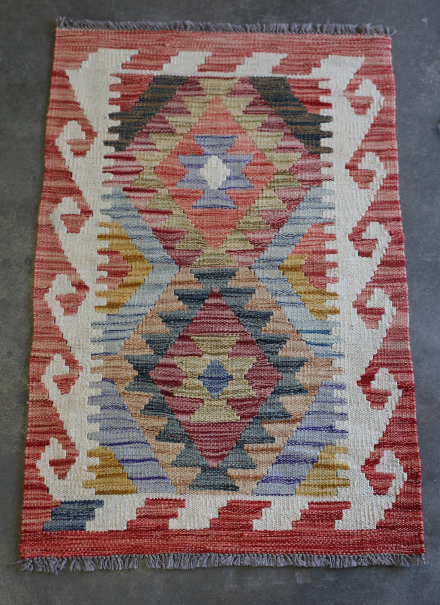 The Afghan Hand Woven Khyber Kilim - 62 X 92. Crafted using traditional vegetable dyed wool, and featuring traditional geometric designs. Colours, oranges, creams, light blues, dark greens. Size 62 X 92. Front.