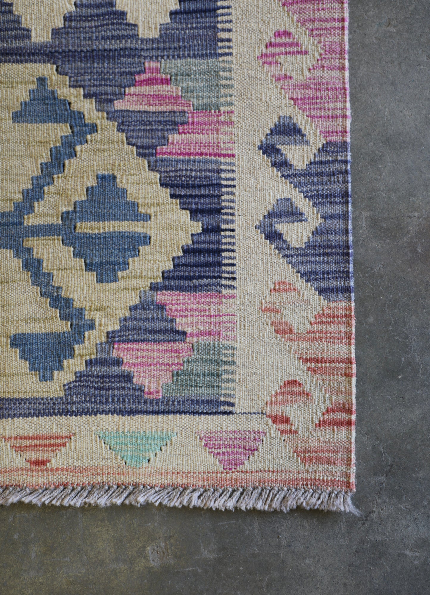 The Afghan Hand Woven Khyber Kilim 63 X 89. Crafted using traditional vegetable dyed wool, and featuring traditional geometric designs. Colours, beiges, light greys, blues. Size 63 X 89. Corner.