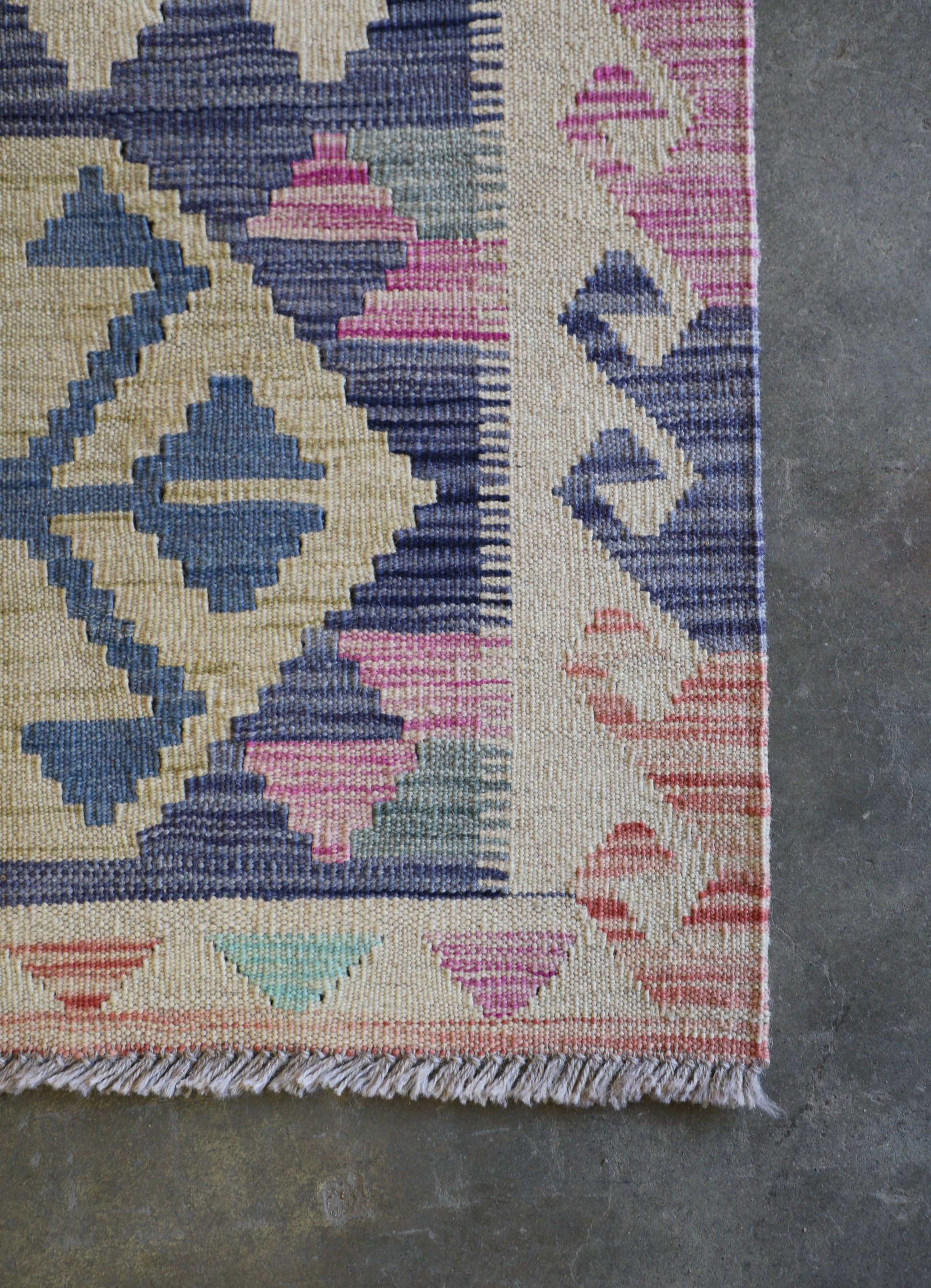 The Afghan Hand Woven Khyber Kilim 63 X 89. Crafted using traditional vegetable dyed wool, and featuring traditional geometric designs. Colours, beiges, light greys, blues. Size 63 X 89. Corner.