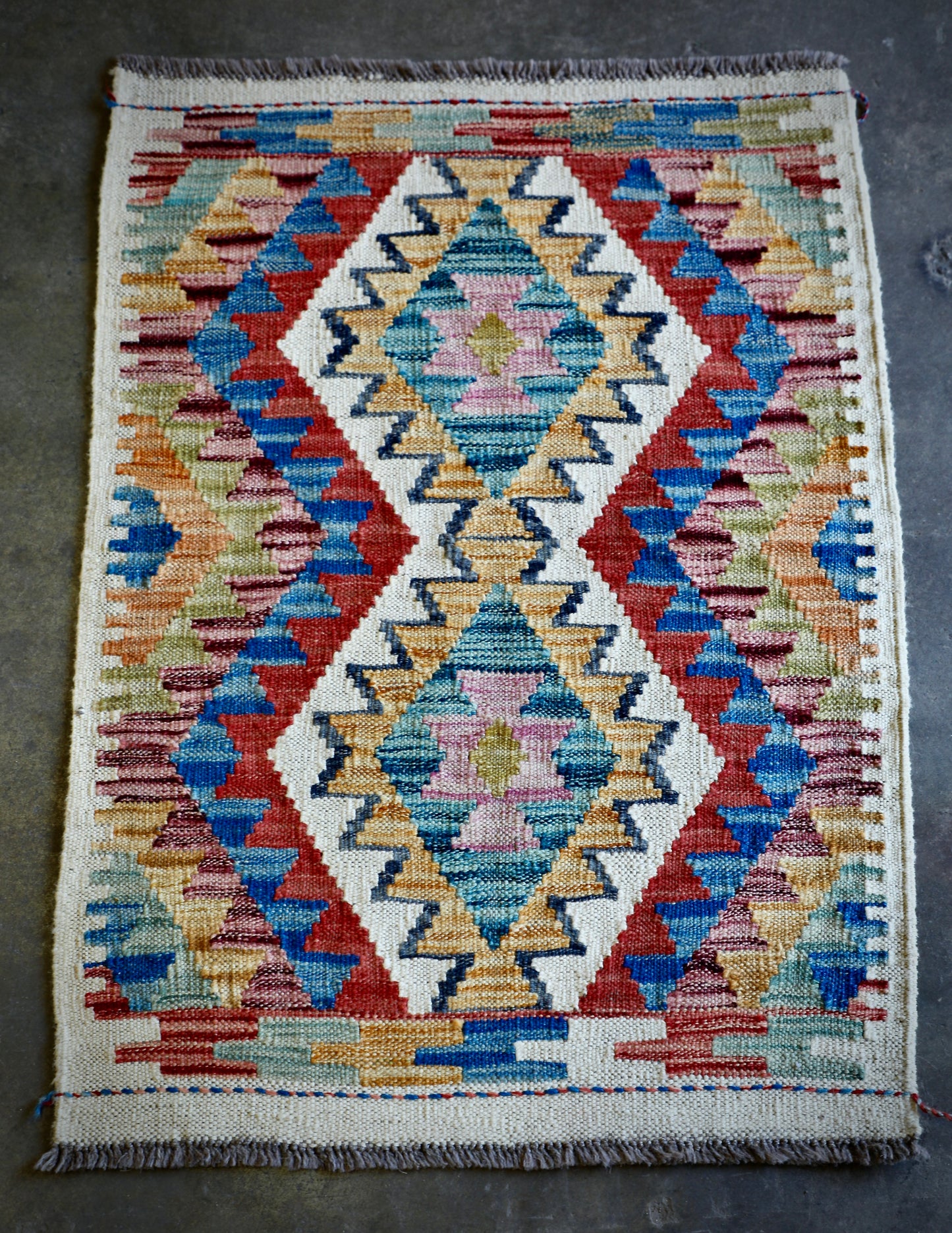 The Afghan Hand Woven Khyber Kilim 66 X 90. Crafted using traditional vegetable dyed wool, and featuring traditional geometric designs. Colours, creams, yellows, oranges, blue and dark greens. Size 66 X 90. Front.