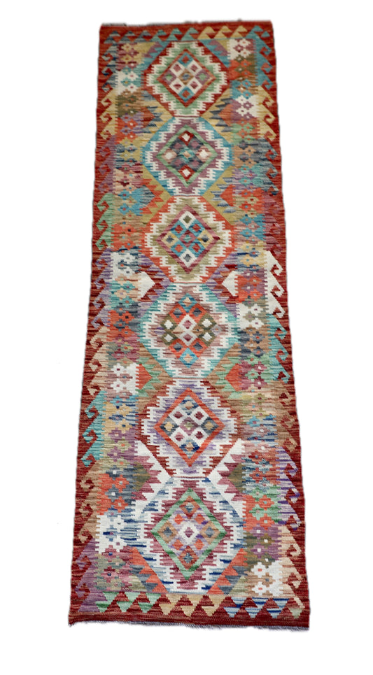 The Afghan Hand Woven Khyber Kilim Runner - 80 X 287. Crafted using traditional vegetable dyed wool, and featuring traditional geometric designs.  Colours, Oranges, reds, yellow, teals and creams. Measures 80 wide X 287 long. Cover.