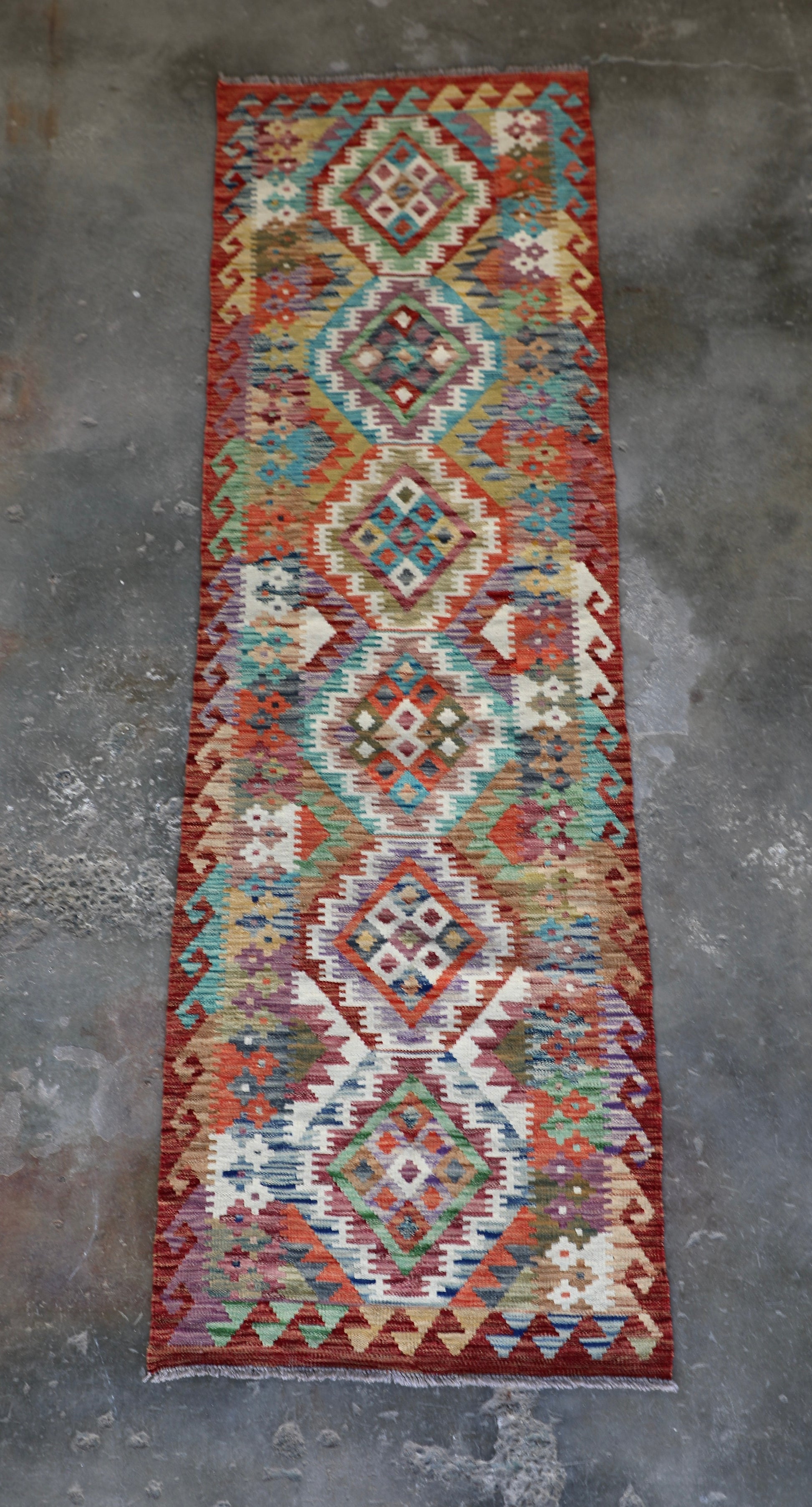 The Afghan Hand Woven Khyber Kilim Runner - 80 X 287. Crafted using traditional vegetable dyed wool, and featuring traditional geometric designs.  Colours, Oranges, reds, yellow, teals and creams. Measures 80 wide X 287 long. Front.