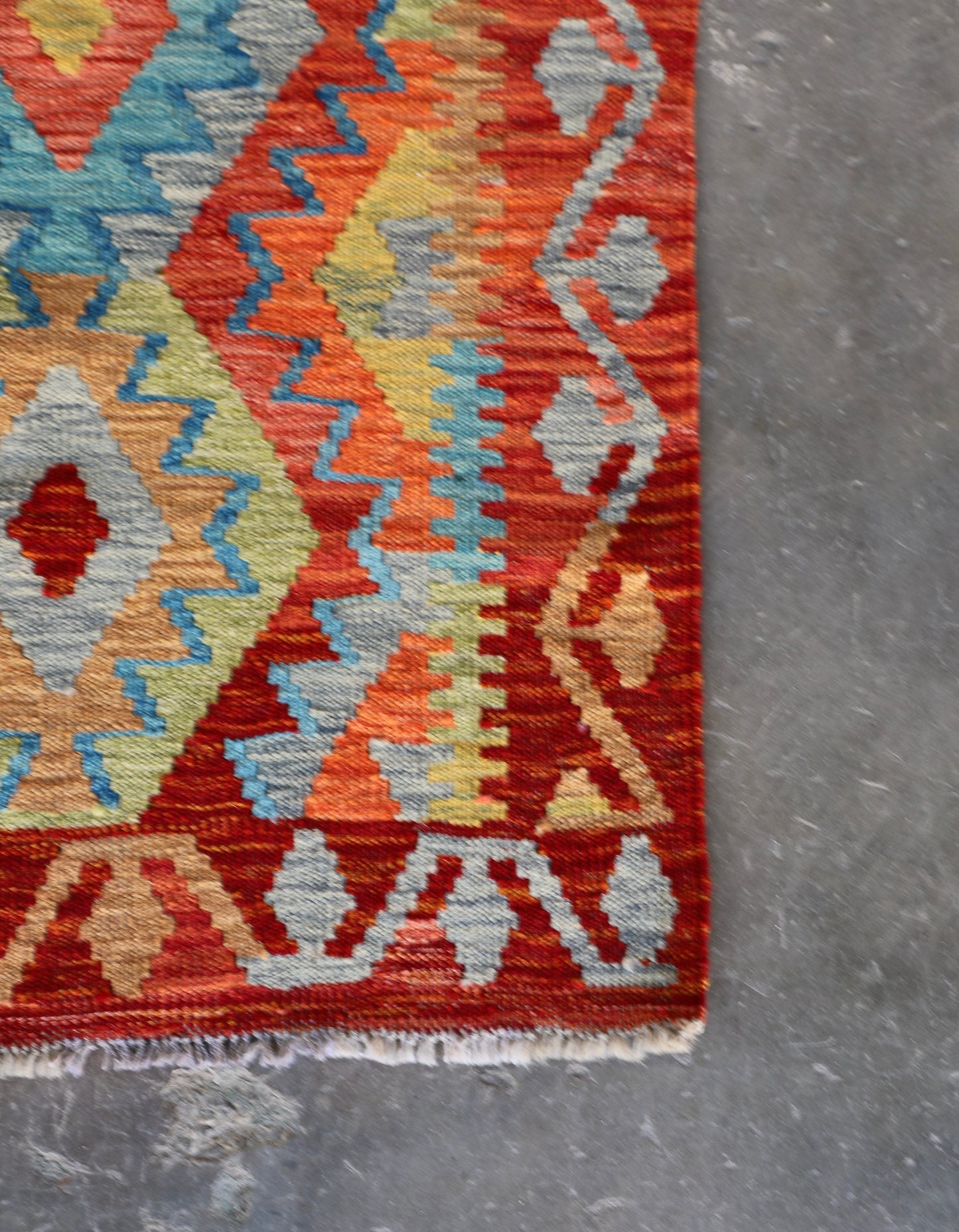 The Afghan Hand Woven Khyber Kilim Runner - 81 X 283. Crafted using traditional vegetable dyed wool, and featuring traditional geometric designs. Colours, reds, oranges, yellows and teal greens. Measures 81 wide X 283 long. Corner.