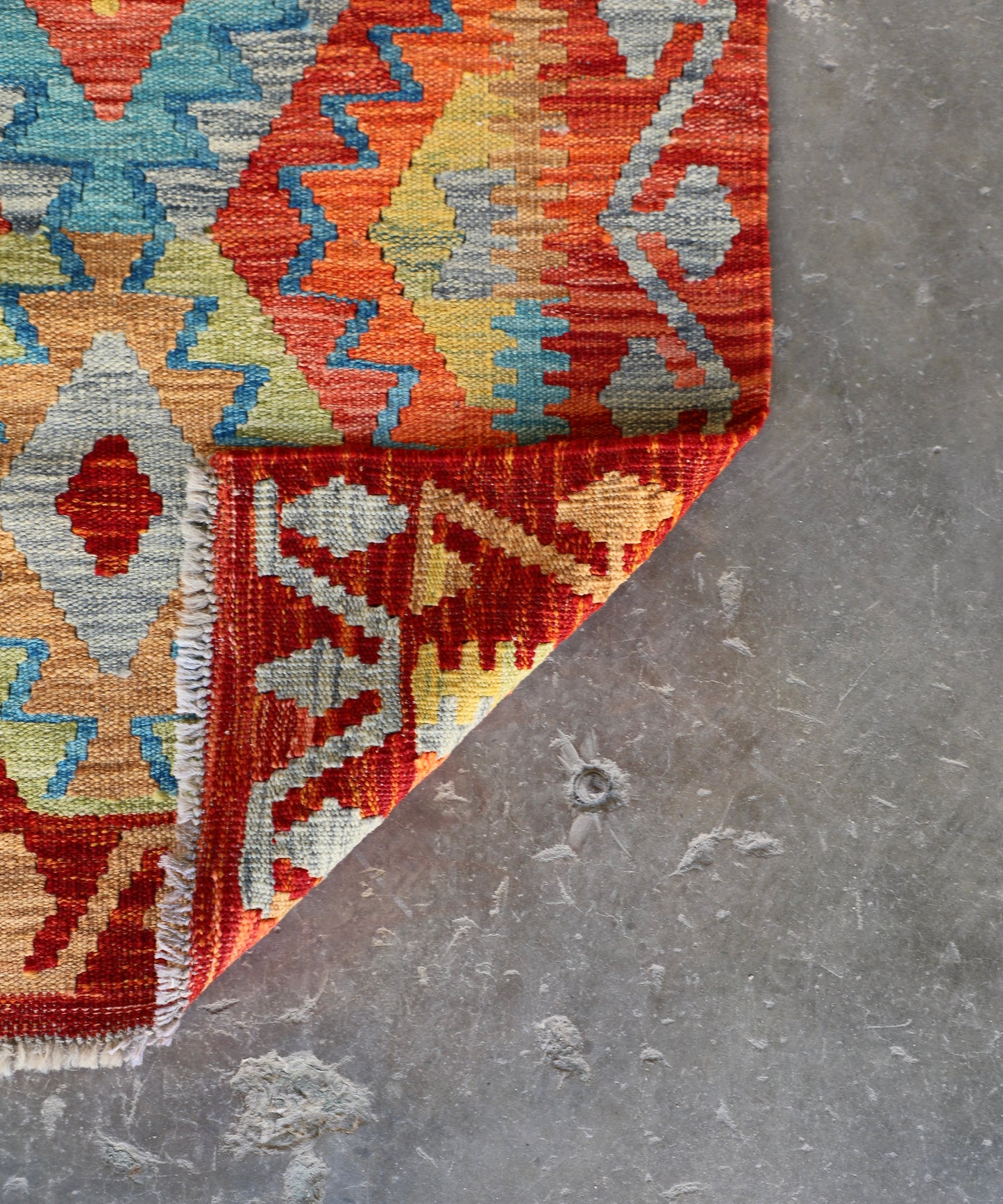 The Afghan Hand Woven Khyber Kilim Runner - 81 X 283. Crafted using traditional vegetable dyed wool, and featuring traditional geometric designs. Colours, reds, oranges, yellows and teal greens. Measures 81 wide X 283 long. Fold.