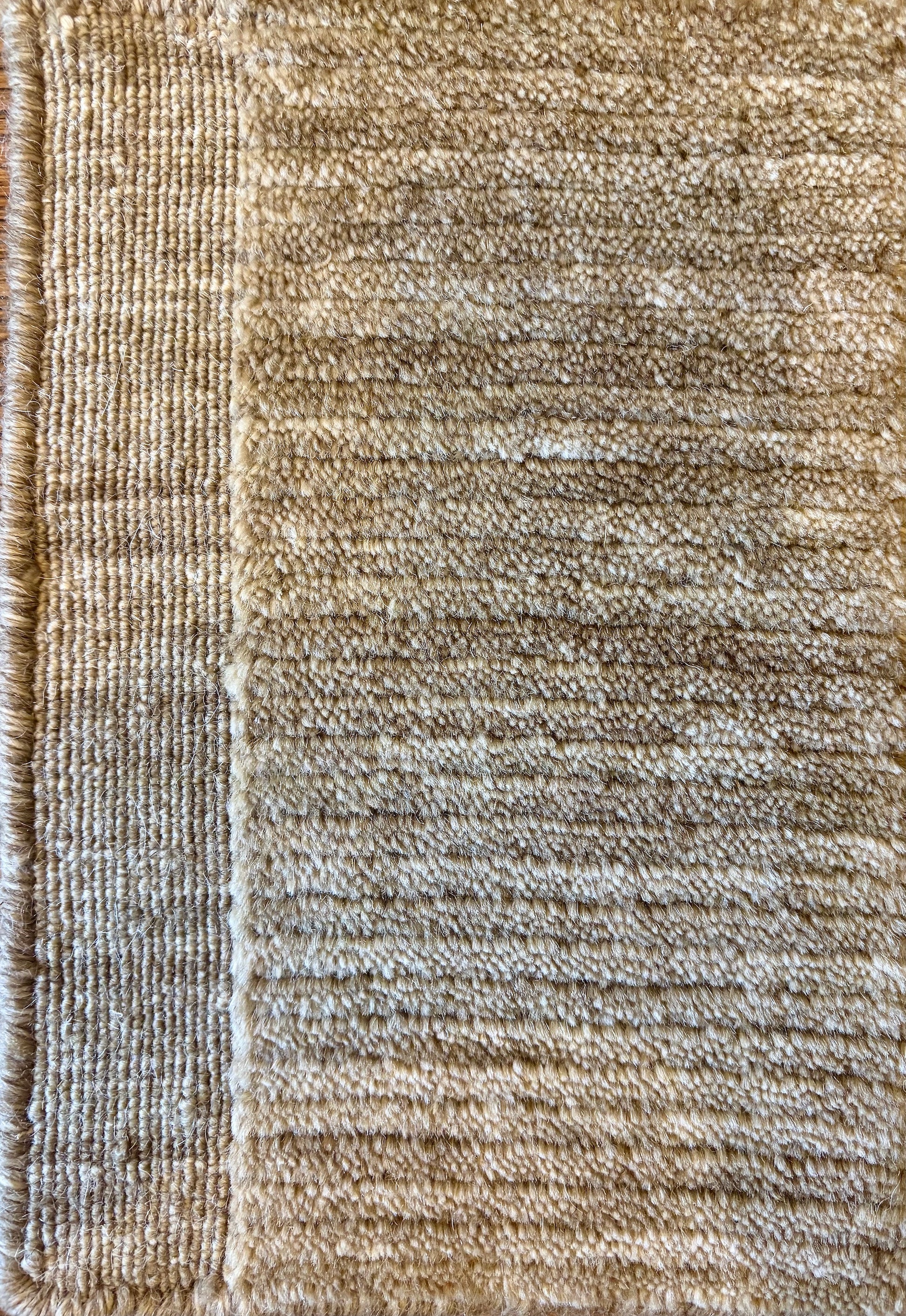 Close-up of the Yarra Camel piled wool rug showing the low channeled pile texture and flat woven border edge. Available in 4 sized. Close view.