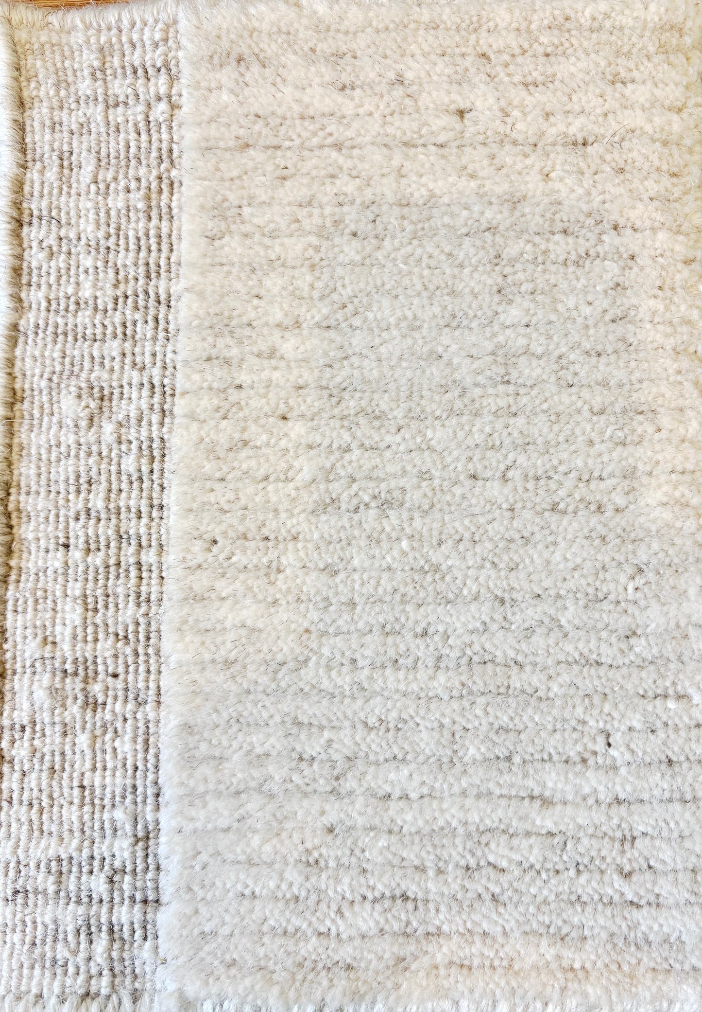 Close-up of the Yarra Ivory piled wool rug showing the low channeled pile texture and flat woven border edge. Available in 4 sized. Close view.