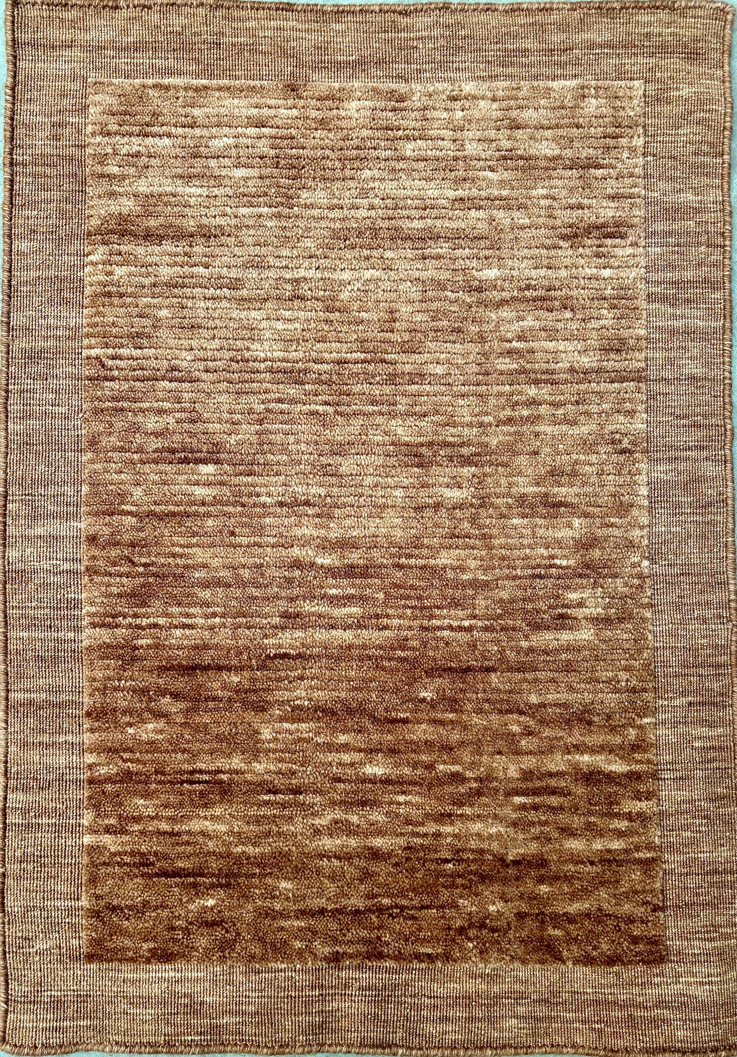 Yarra Rust piled hand-woven wool rug in a warm earthy terracotta tone with a low channeled pile and flat woven border. Available in 4 sizes. Top View.
