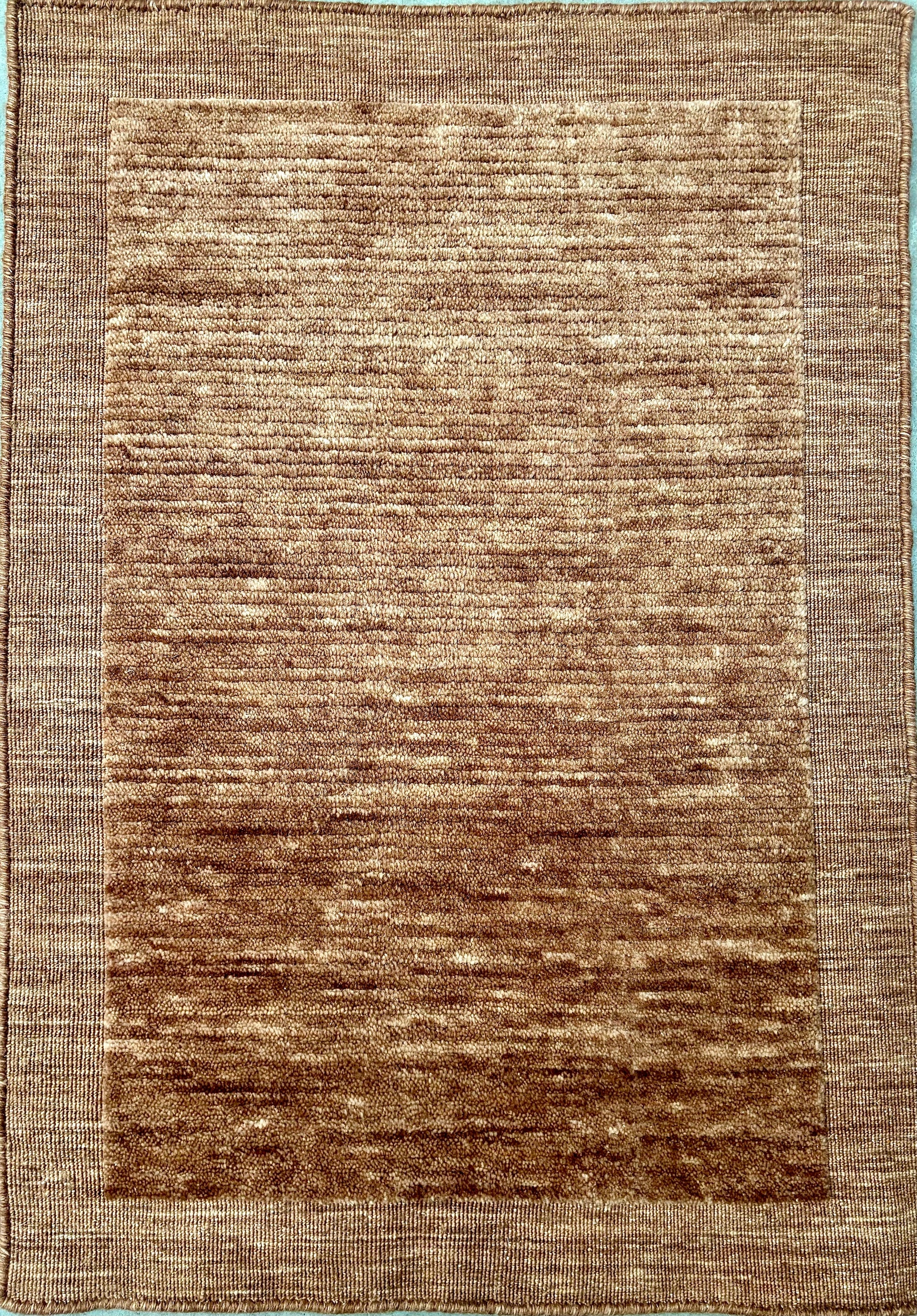 Yarra Rust piled hand-woven wool rug in a warm earthy terracotta tone with a low channeled pile and flat woven border. Available in 4 sizes. Top View.
