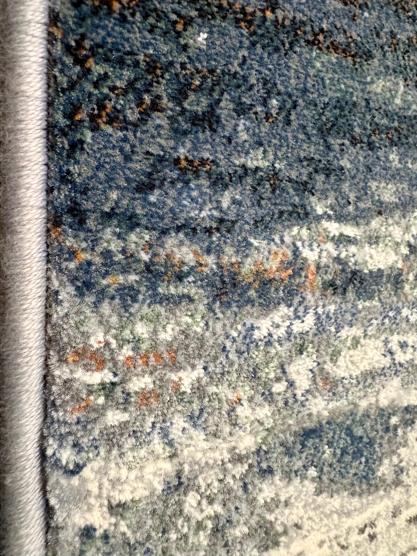 The Zenith Strata rug. This rug is skilfully created from strong heat-set polypropylene, showcasing a stylish contemporary design. Colours, whites, greys, blues, beiges. Side Close.