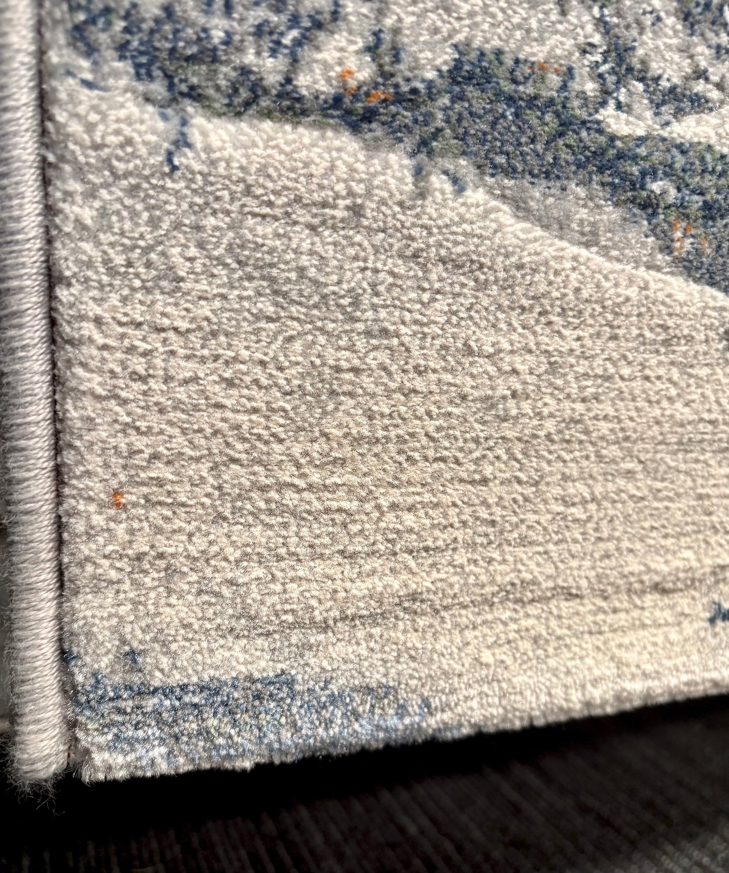 The Zenith Terrain rug. This rug is skilfully crafted from heat-set polypropylene, showcasing a stylish contemporary design. Colours, whites, blues beiges, dark greys. Corner.